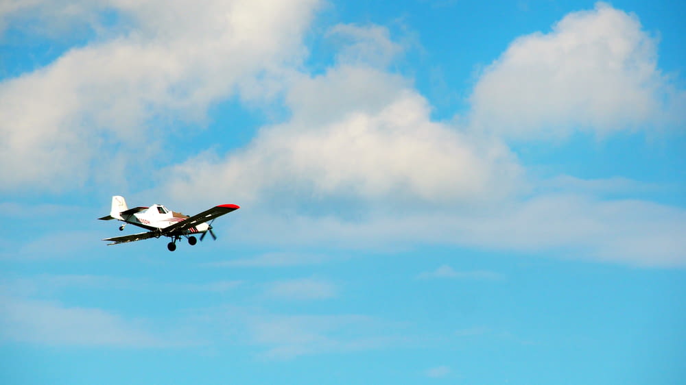 white and red airplane flying under blue sky during daytime