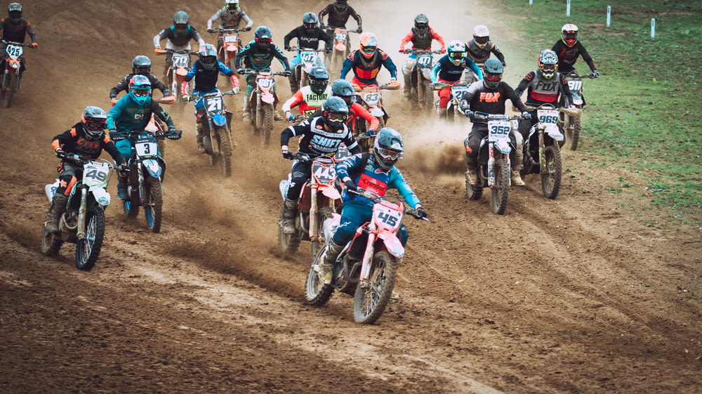 people riding motorcycle racing on dirt track during daytime