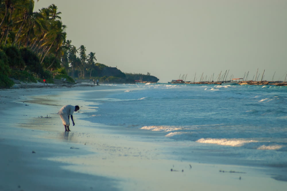 man in white shirt walking on beach during daytime