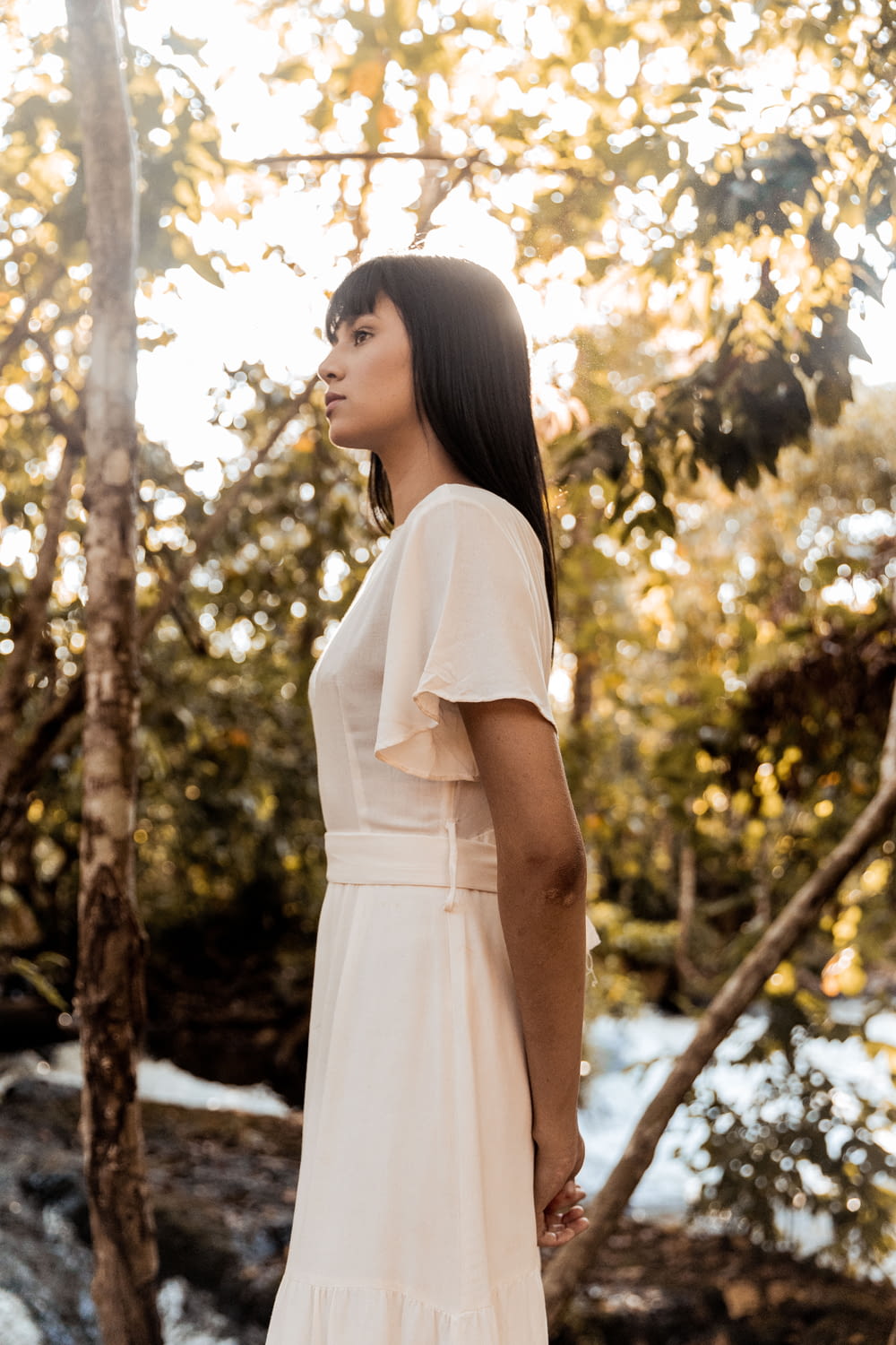 woman in white dress standing near trees during daytime