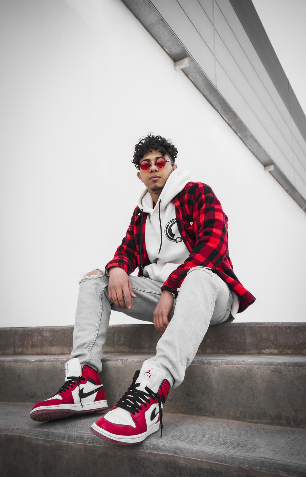 man in red and white jacket sitting on concrete stairs