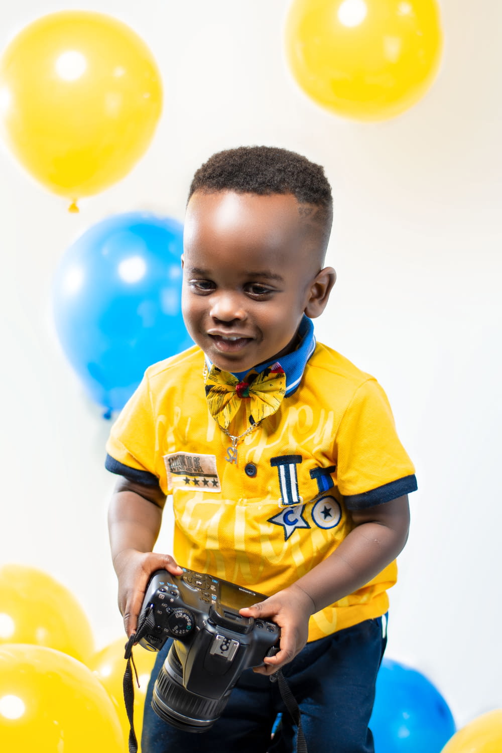 boy in yellow and blue polo shirt holding blue and black toy gun