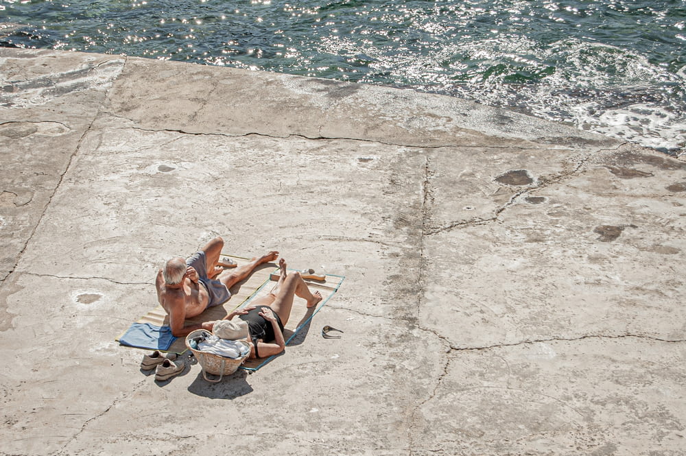 낮 동안 수역 근처의 콘크리트 바닥에 누워있는 2 명의 여성
