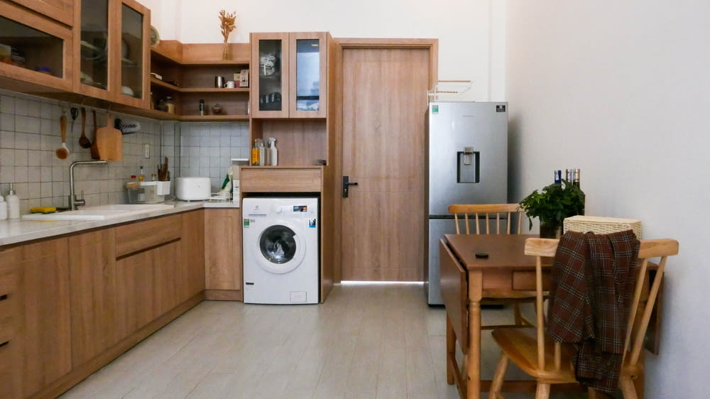 white front load washing machine beside brown wooden cabinet