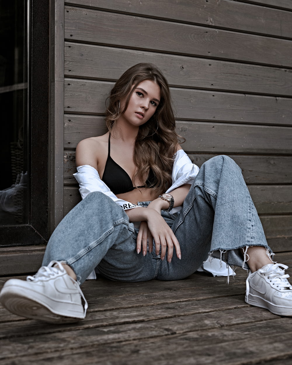 woman in blue spaghetti strap top and blue denim jeans sitting on brown wooden floor