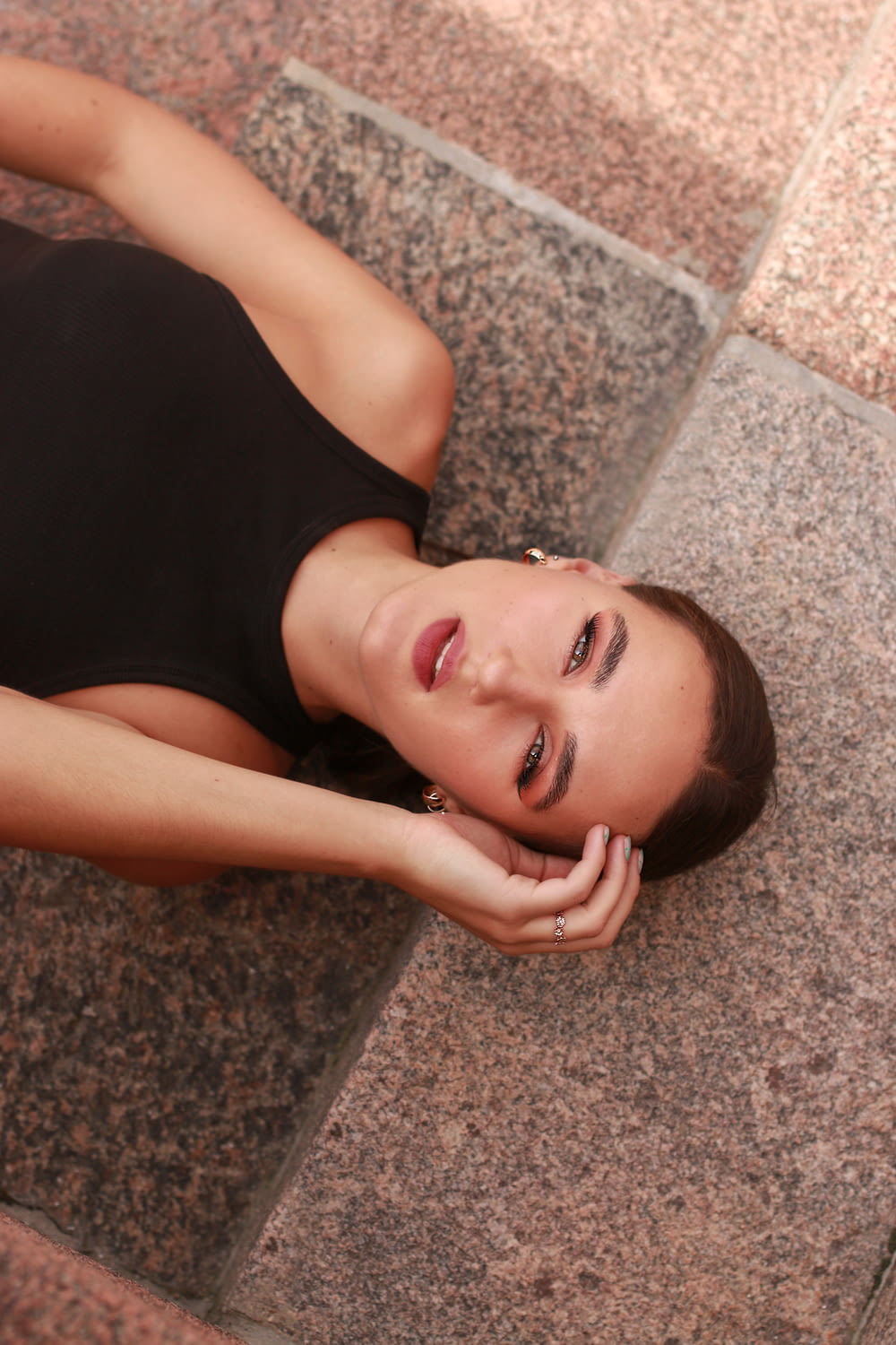 woman in black tank top lying on concrete floor