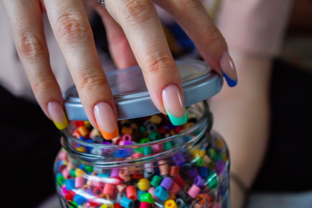 person holding clear glass jar with candies