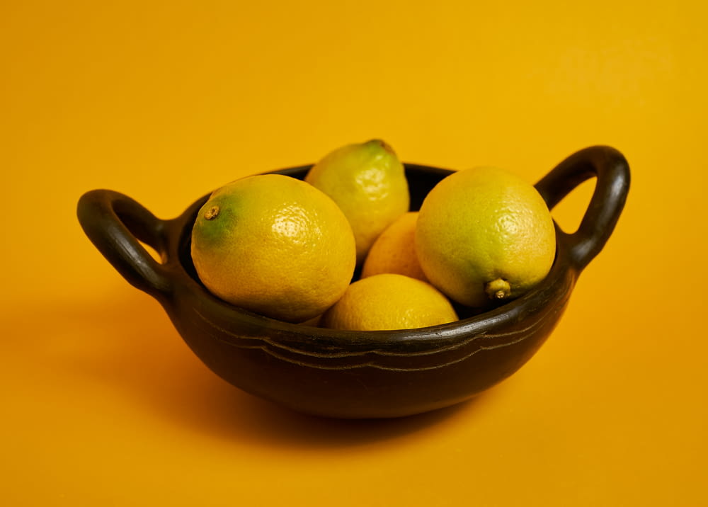 yellow citrus fruits on black ceramic bowl