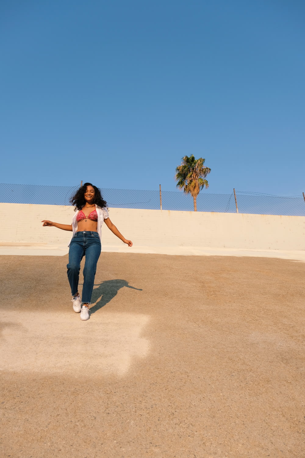 donna in jeans blu denim che cammina sulla sabbia marrone durante il giorno