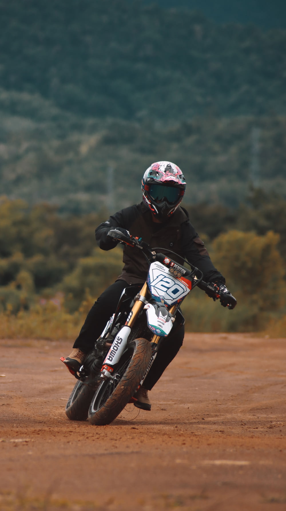 Hombre con chaqueta negra montando en una moto de cross de motocross naranja y blanca