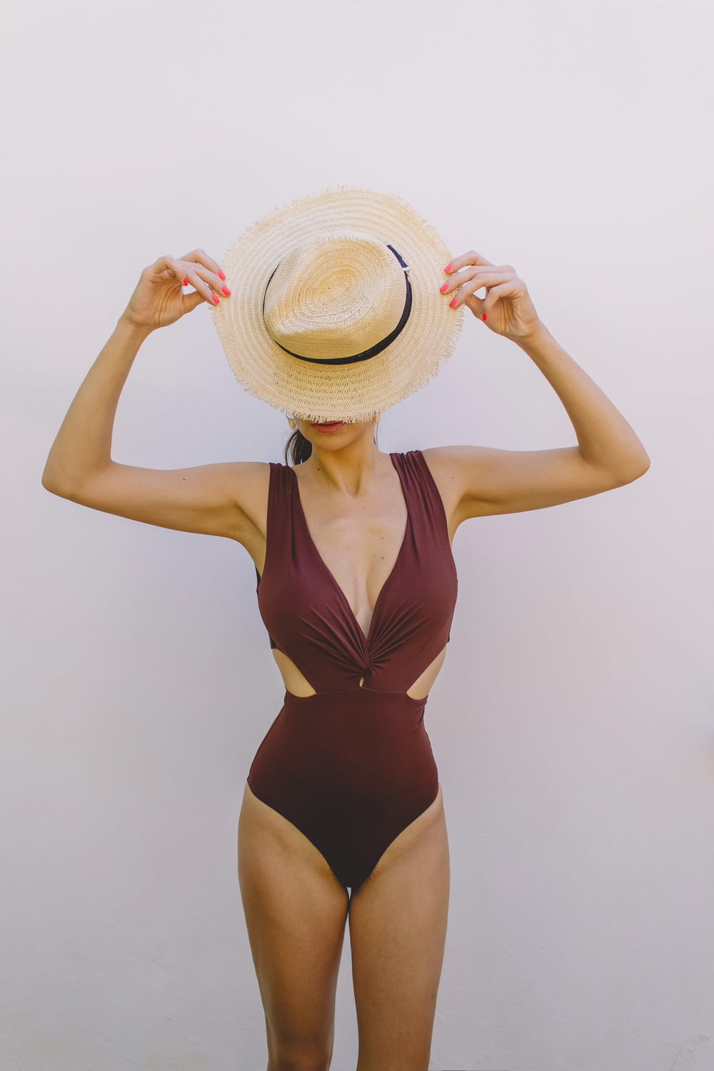 Femme en maillot de bain une pièce marron portant un chapeau de soleil marron
