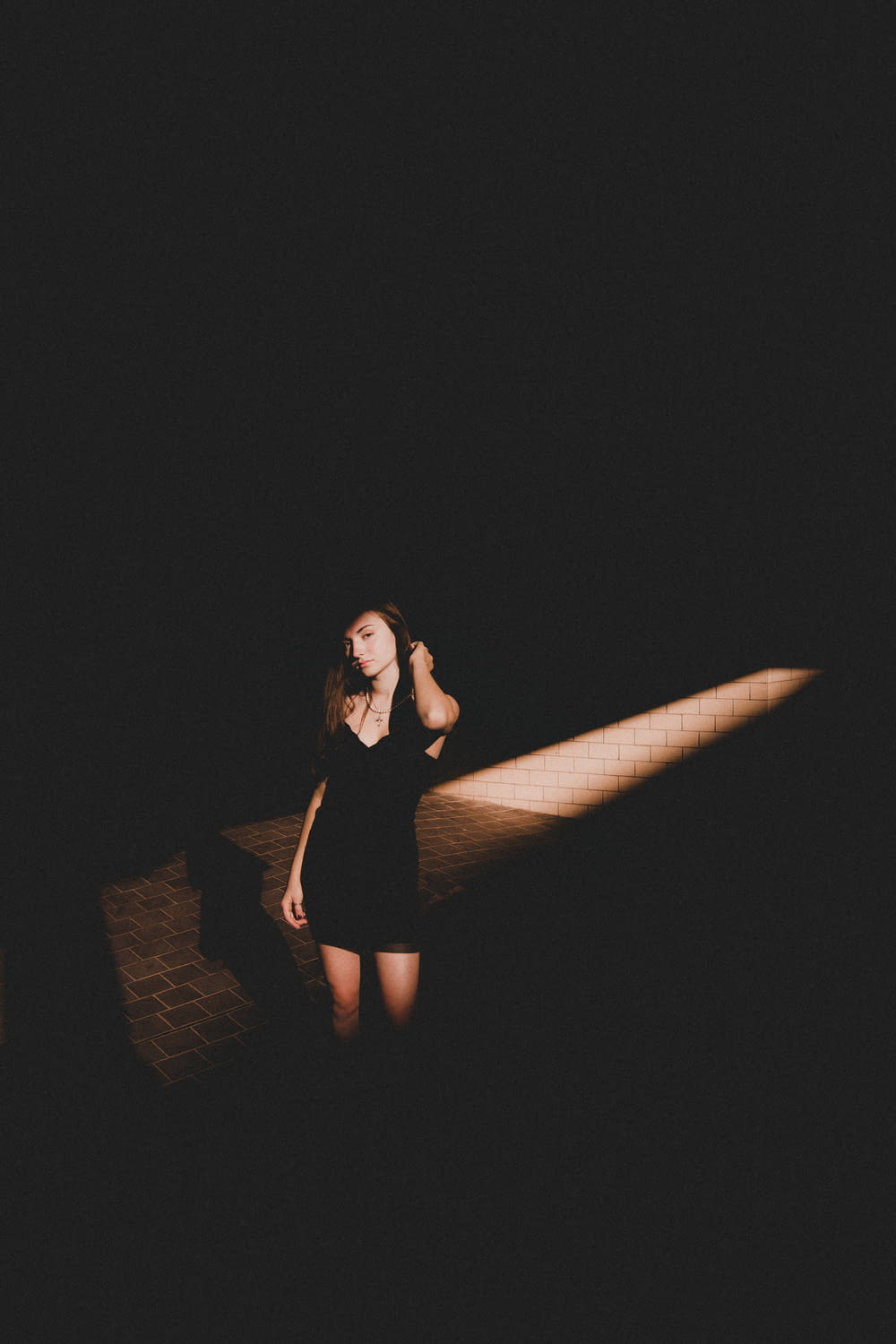 woman in black dress sitting on brown brick wall