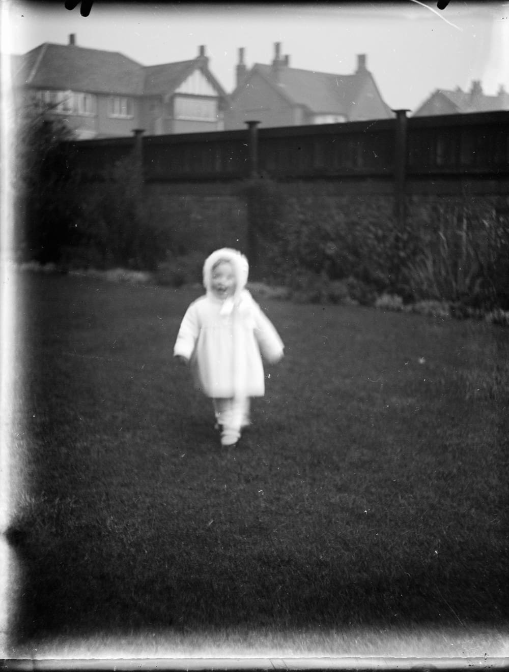 grayscale photo of child in white long sleeve shirt standing on grass field