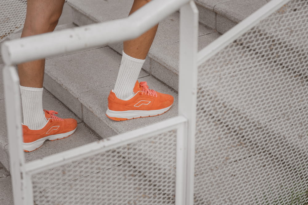 person in orange and white nike sneakers