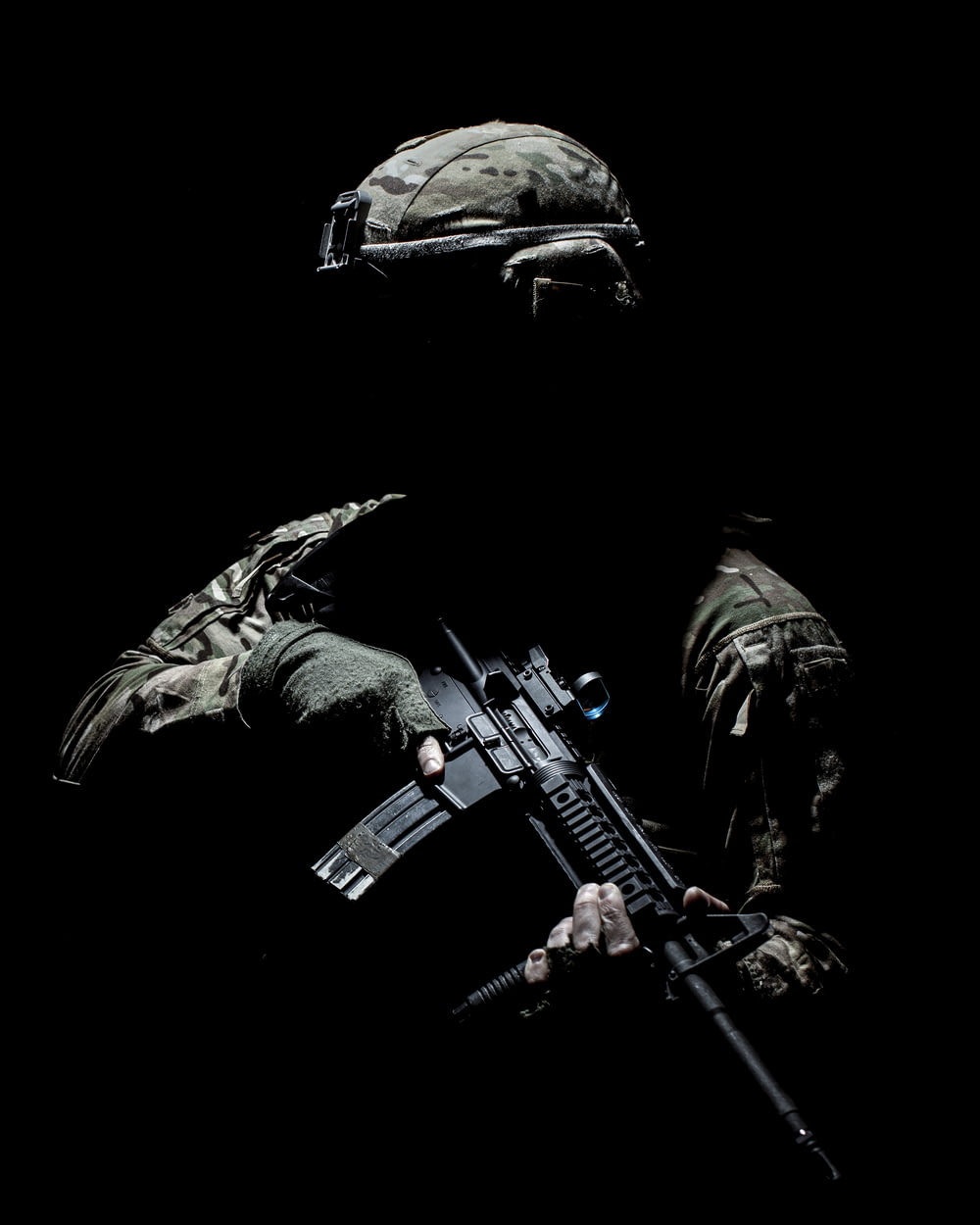 homem no terno de camuflagem preto e verde segurando rifle