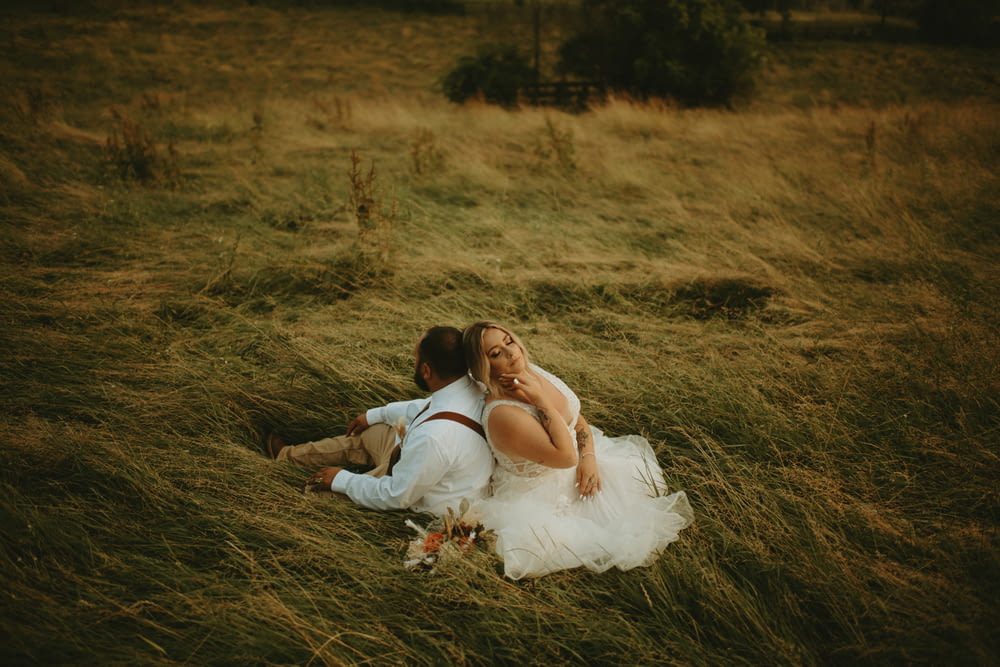 茶色の草の上に横たわる白いドレスの女性