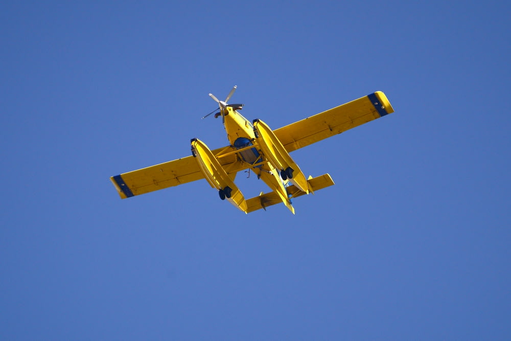avião amarelo e preto no ar sob o céu azul durante o dia
