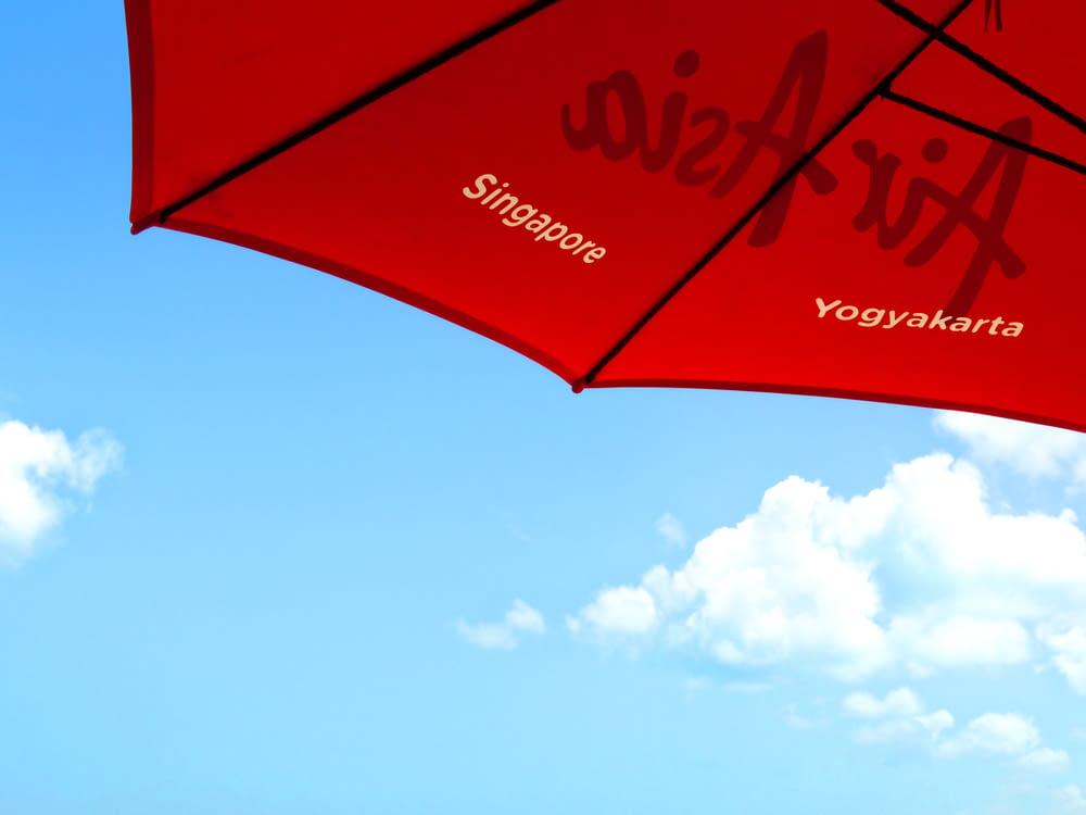 昼間の青空に赤と白の傘