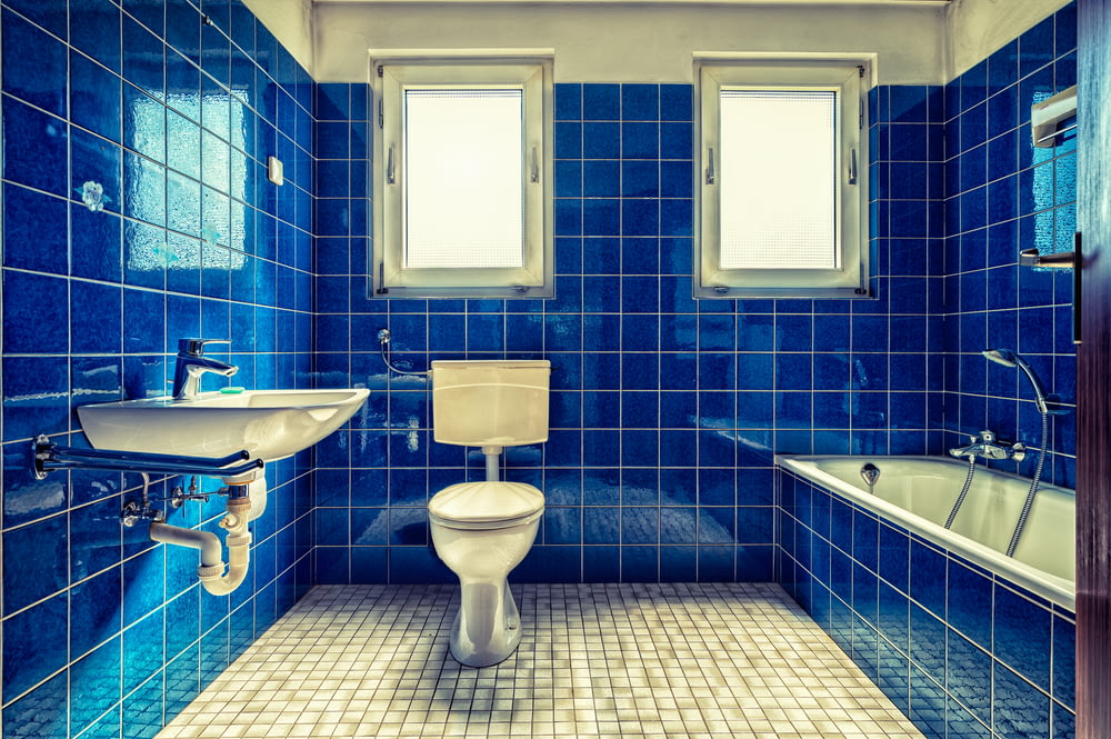 white ceramic sink beside blue wall tiles