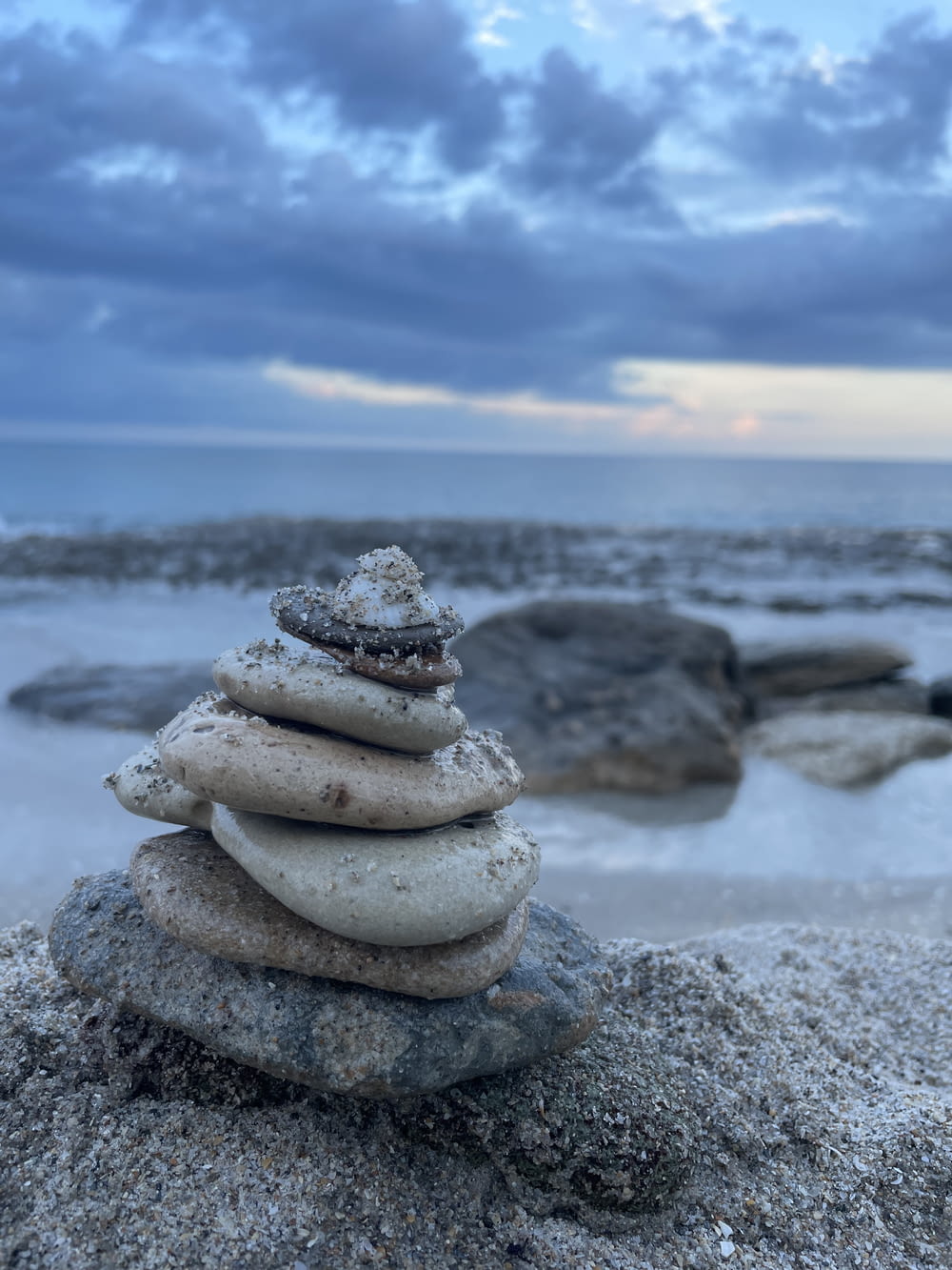 Grauer und brauner Stein auf grauem Sand in der Nähe von Gewässern tagsüber
