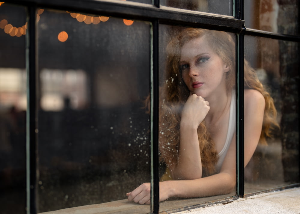 girl in white sleeveless dress sitting on window