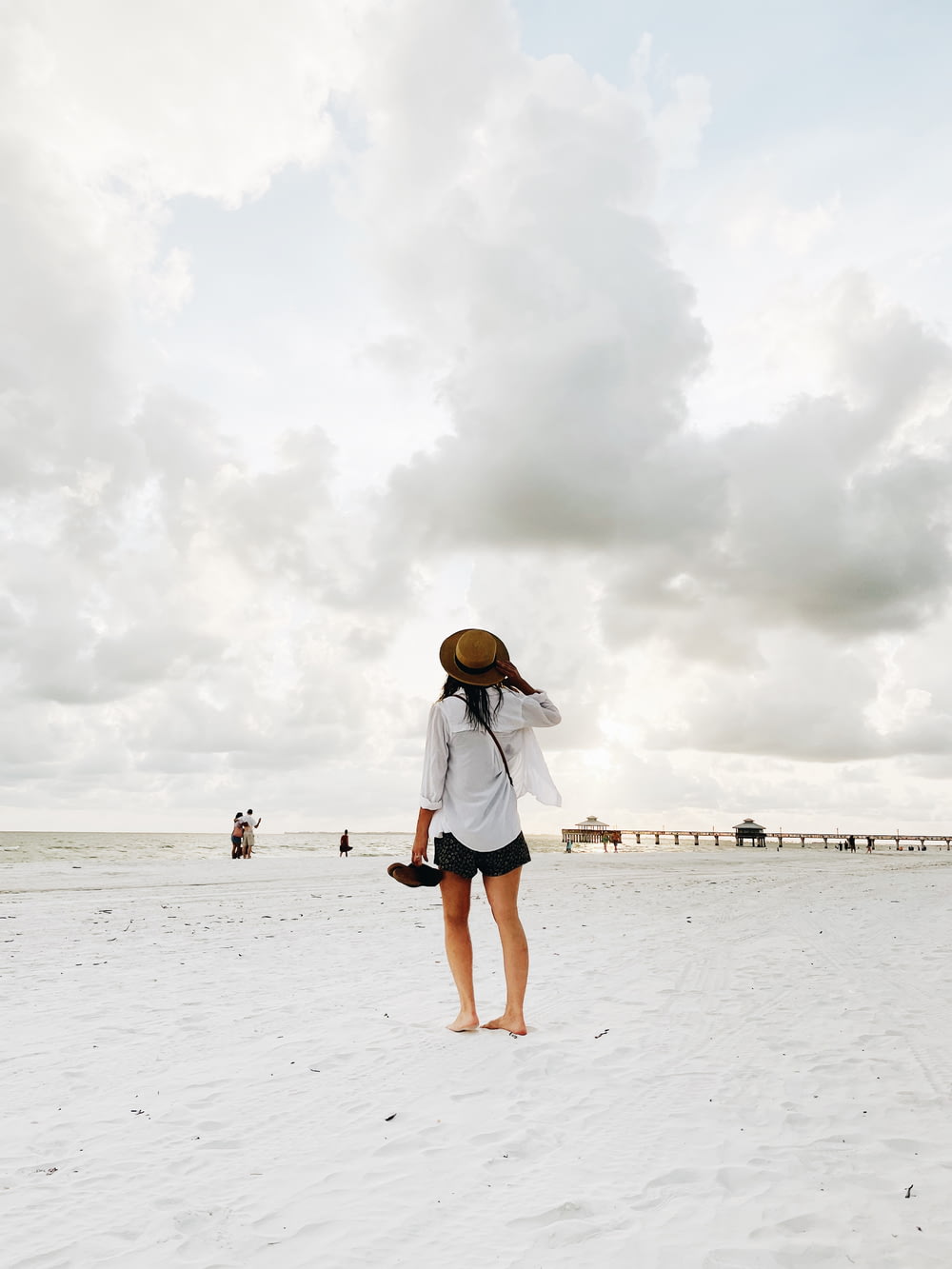 Femme en chemise blanche et short en jean bleu debout sur la plage pendant la journée