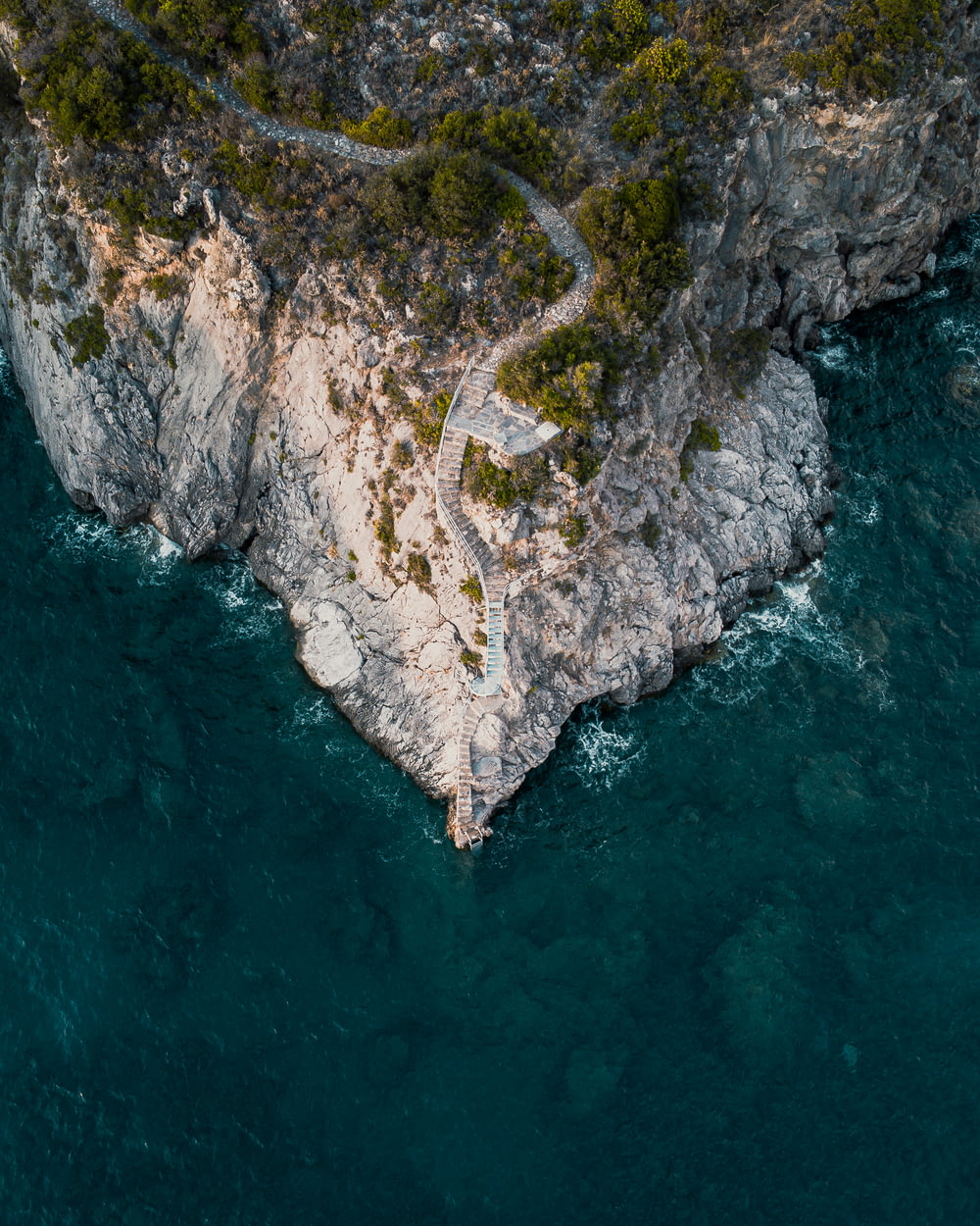 vista aérea da montanha verde e marrom ao lado do corpo de água durante o dia