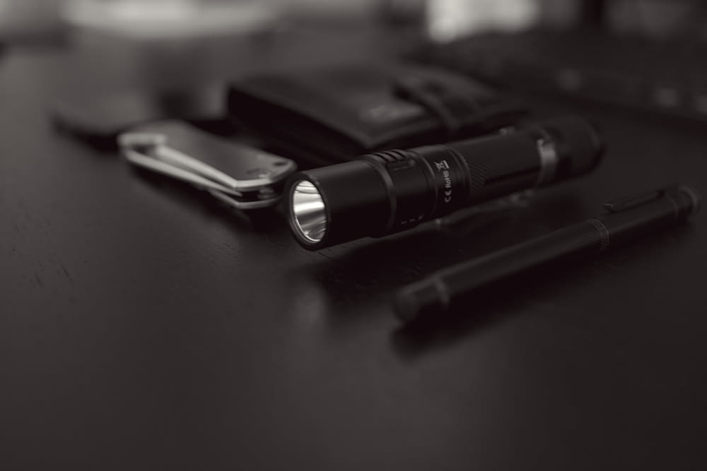 a black and white photo of a flashlight and a cell phone