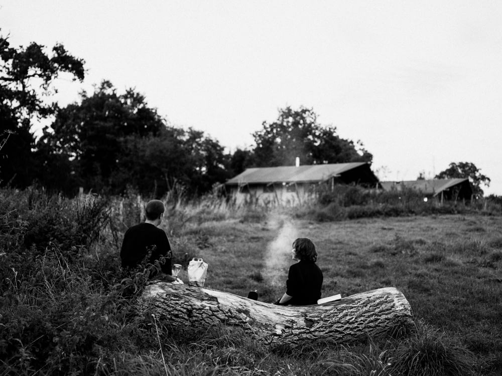 two people sitting on a log in a field