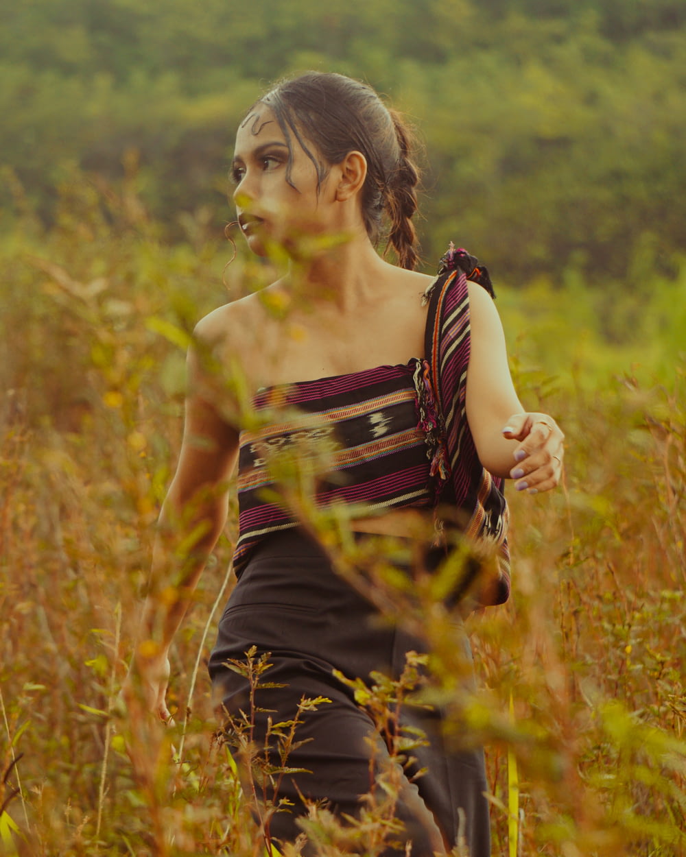 a young girl walking through a field of tall grass