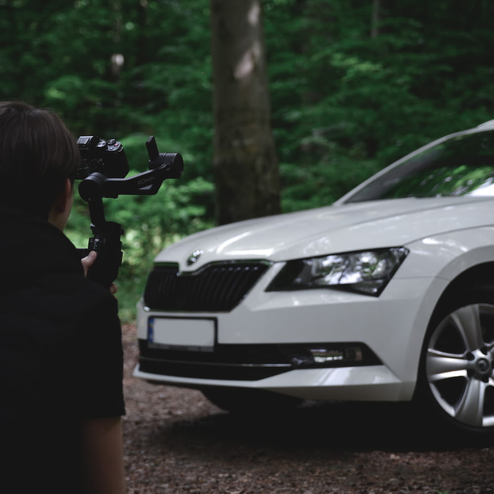 a person is filming a car in the woods