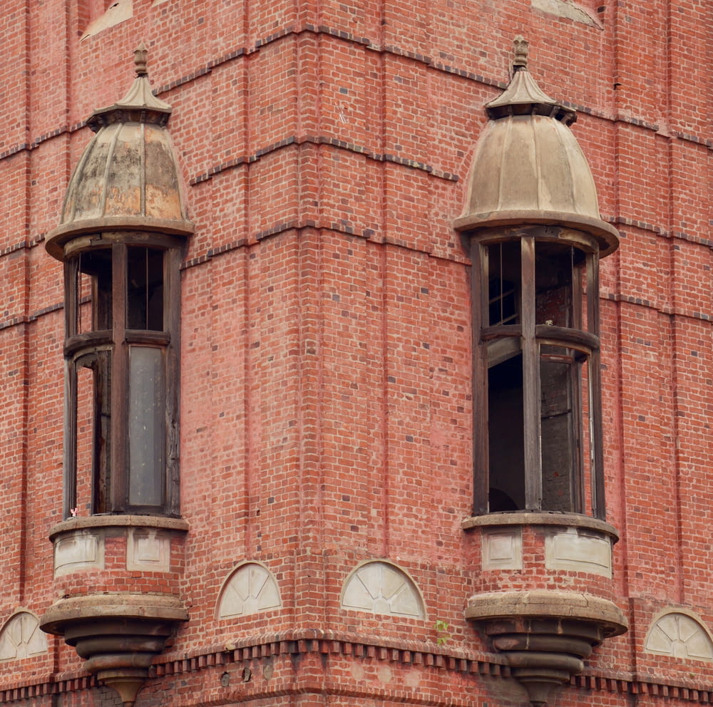 a red brick building with two windows and a clock