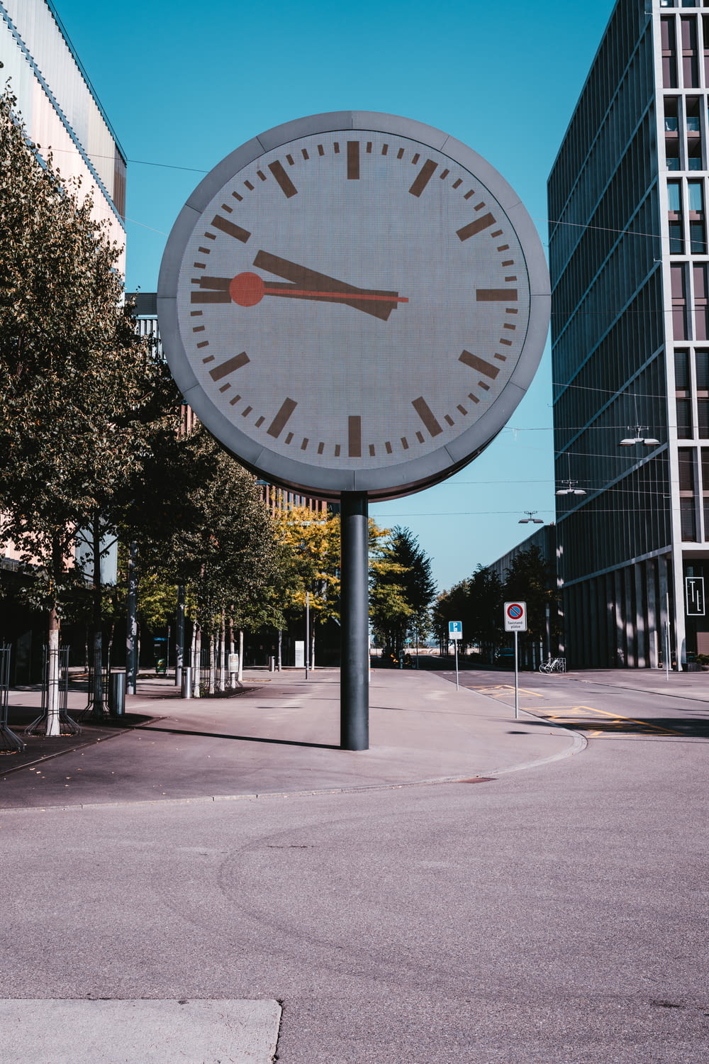 a large clock on a pole in the middle of a street
