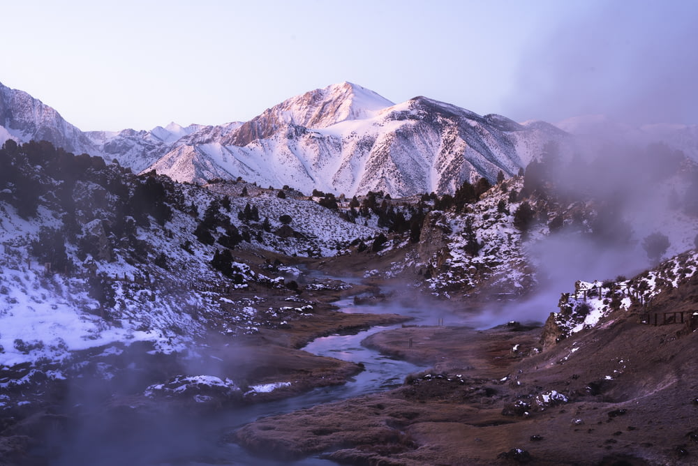 a mountain range covered in snow and steam