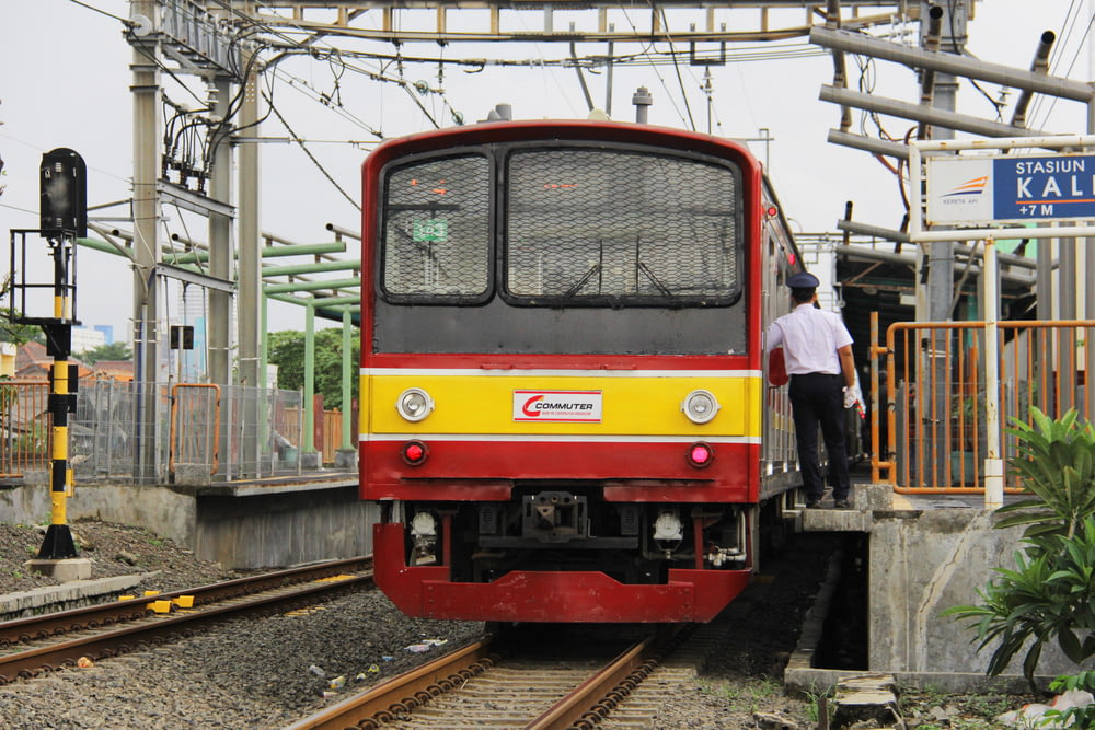 a red and yellow train pulling into a train station