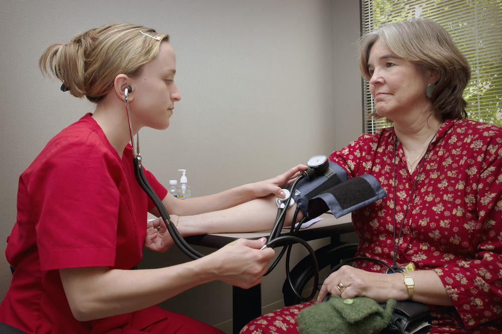 Una donna con uno stetoscopio che ascolta un paziente
