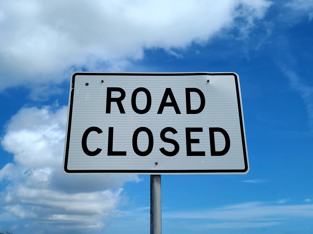 a road closed sign in front of a blue sky