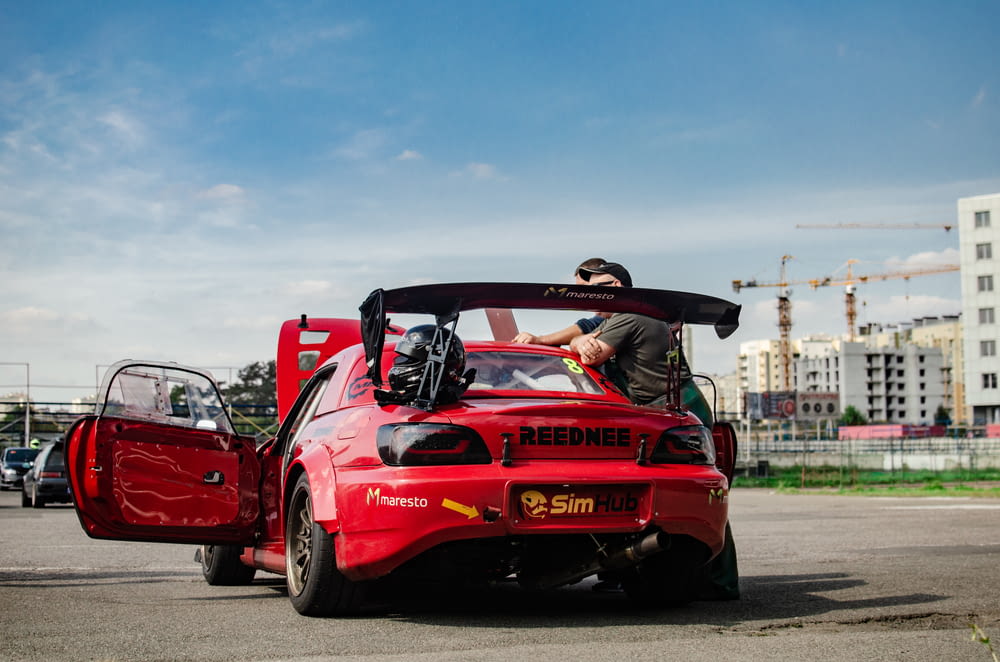 a red sports car with a man sitting in the back of it