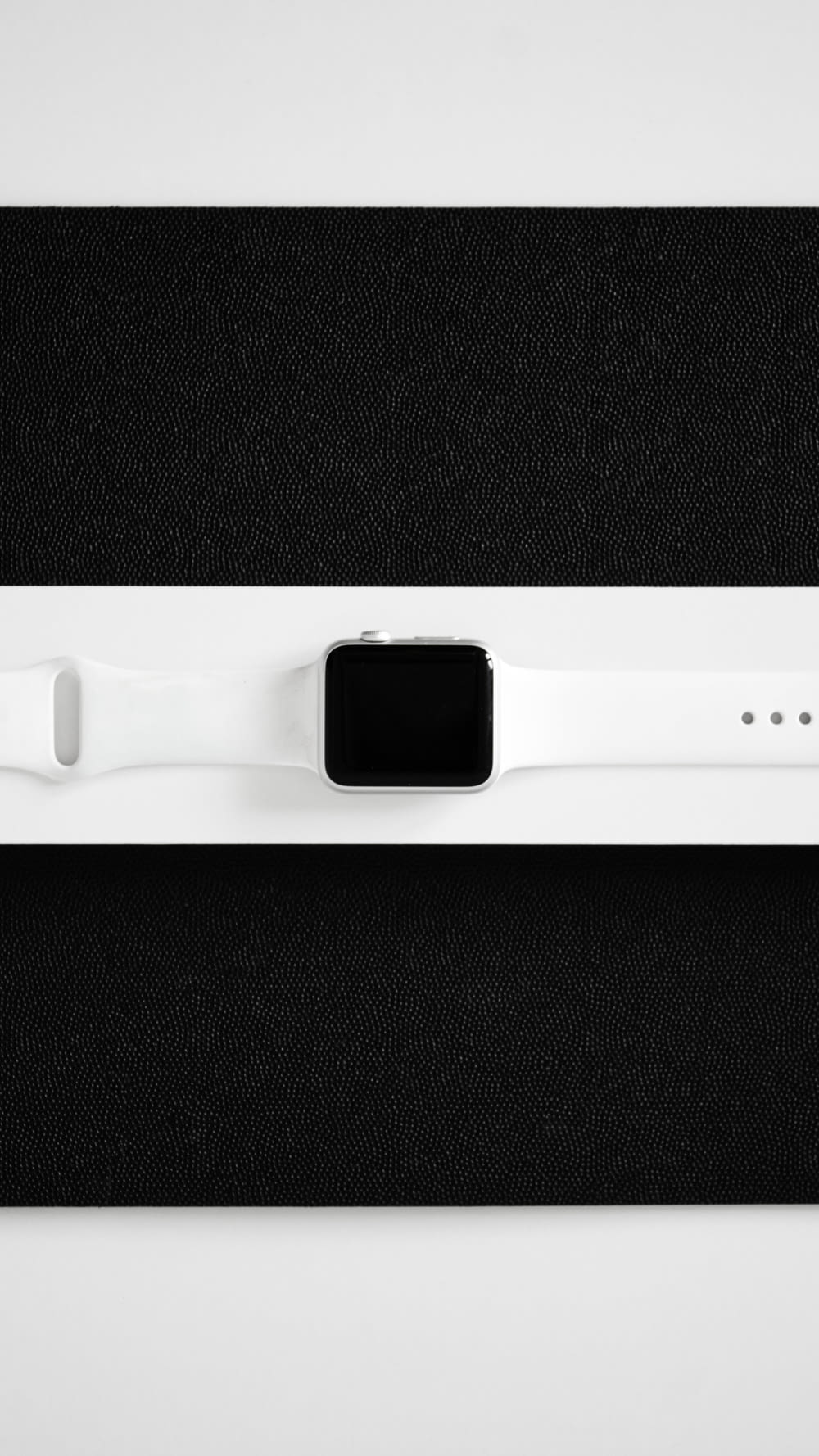 a white apple watch sitting on top of a black surface