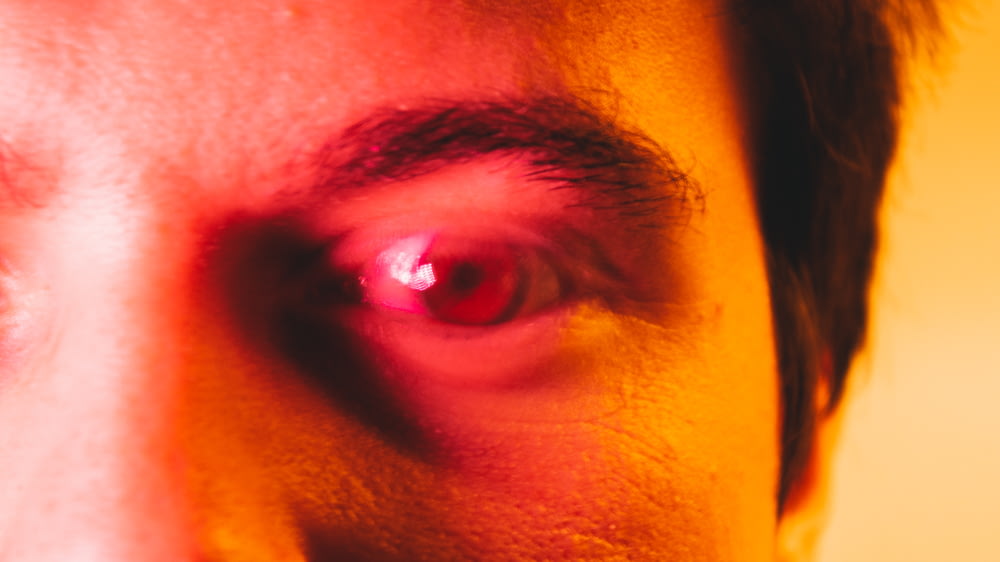 赤い光が当たる男の目の接写