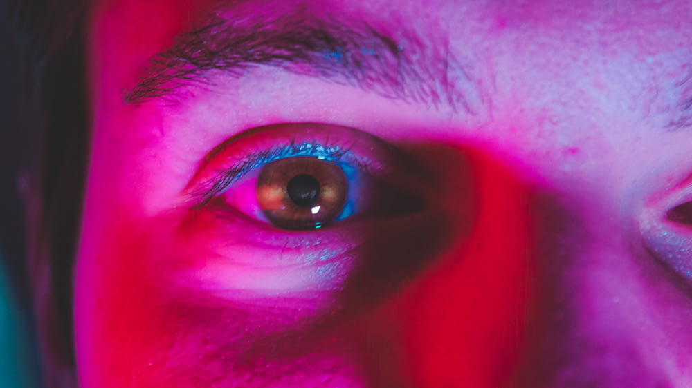 赤と青の背景を持つ人の目の接写