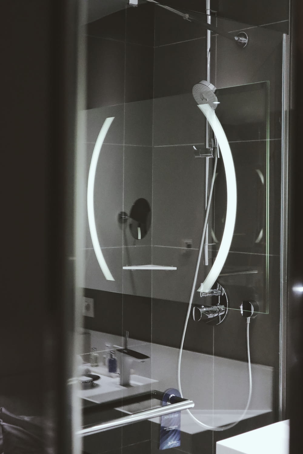 une salle de bain avec lavabo, miroir et pommeau de douche