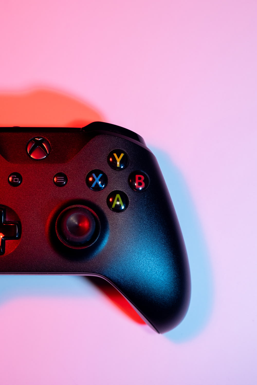 a close up of a black controller on a pink background