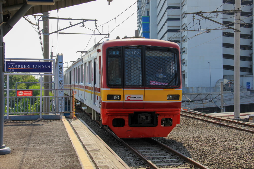 a red and yellow train pulling into a train station