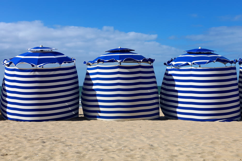 a row of blue and white striped umbrellas sitting on top of a sandy beach