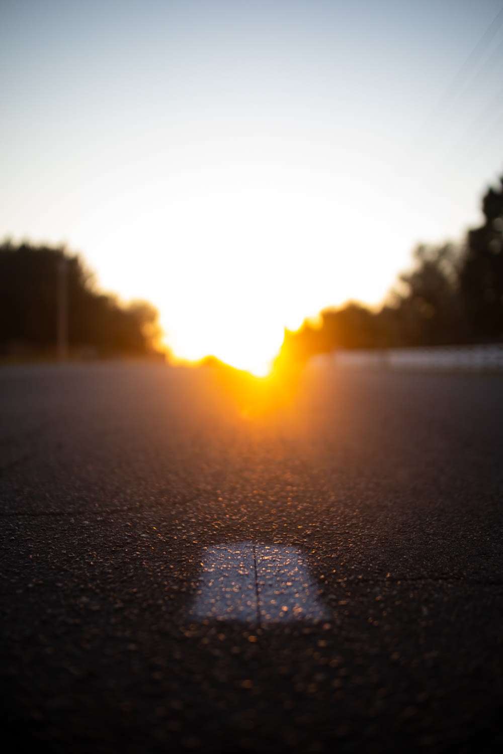 the sun is setting over a street with a shadow on the ground