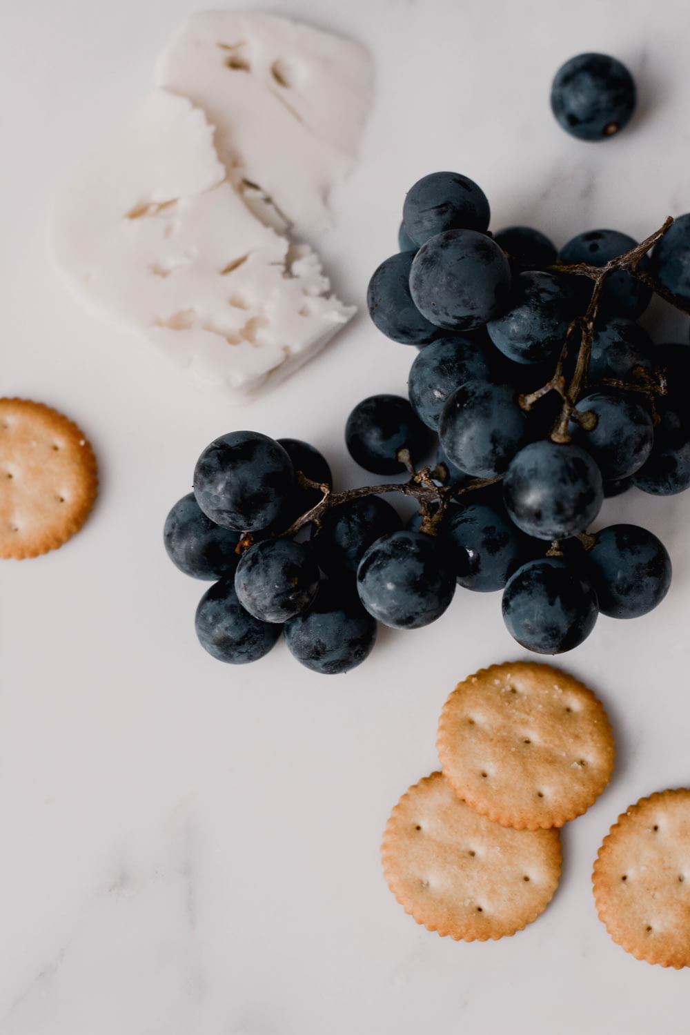 grapes, crackers and cheese on a marble surface