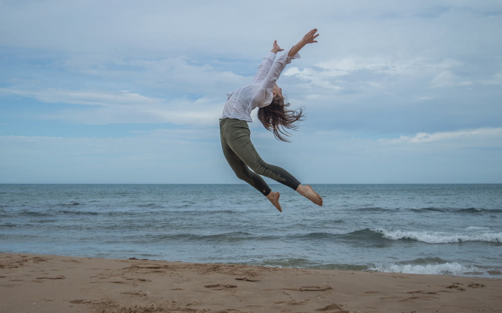 a woman jumping in the air on a beach