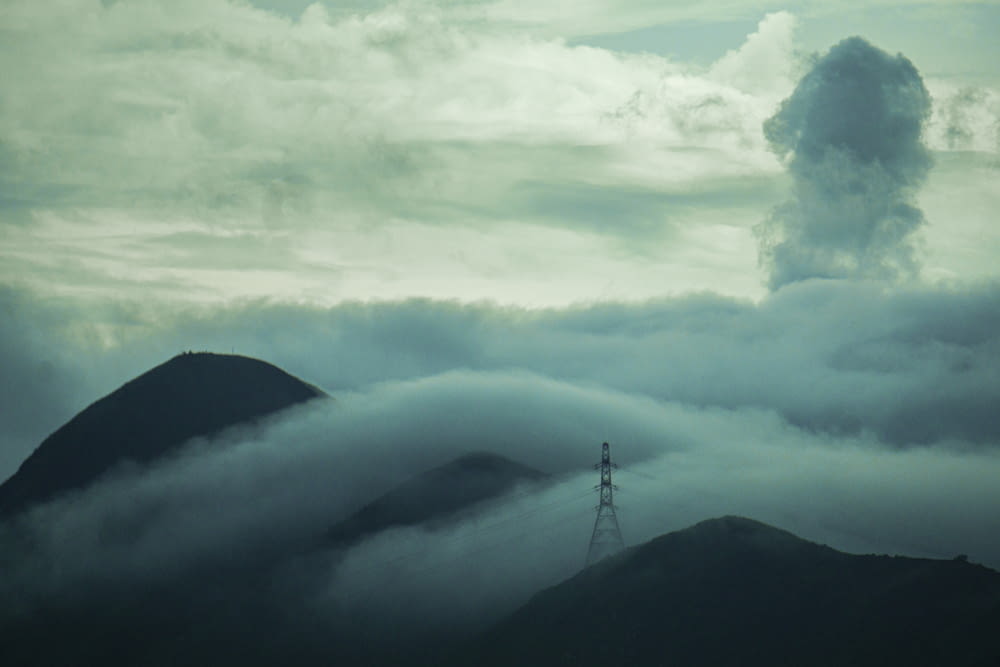 a mountain covered in clouds with a tower in the distance