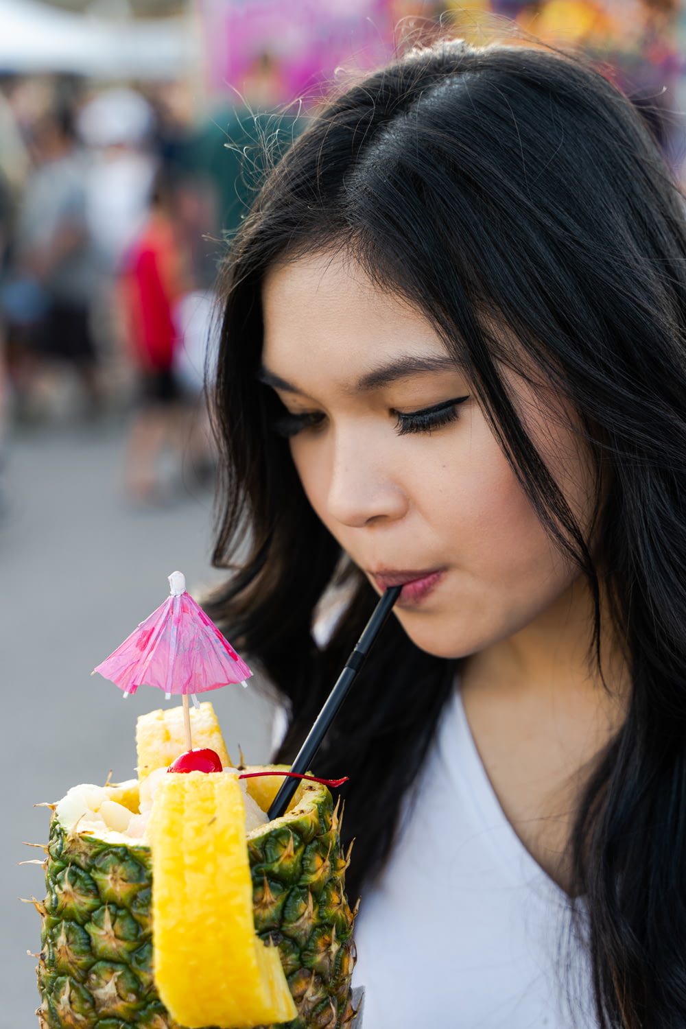 Une femme tenant un ananas avec une paille dans la bouche